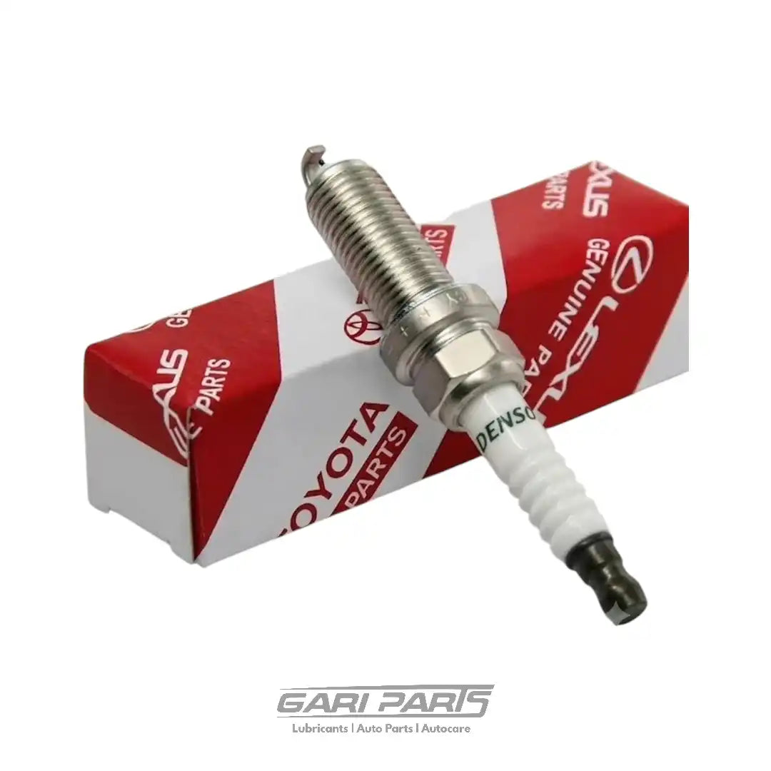 A Toyota genuine spark plug with a white ceramic insulator and a silver metal electrode, resting on its red and white branded packaging box against a white background.
